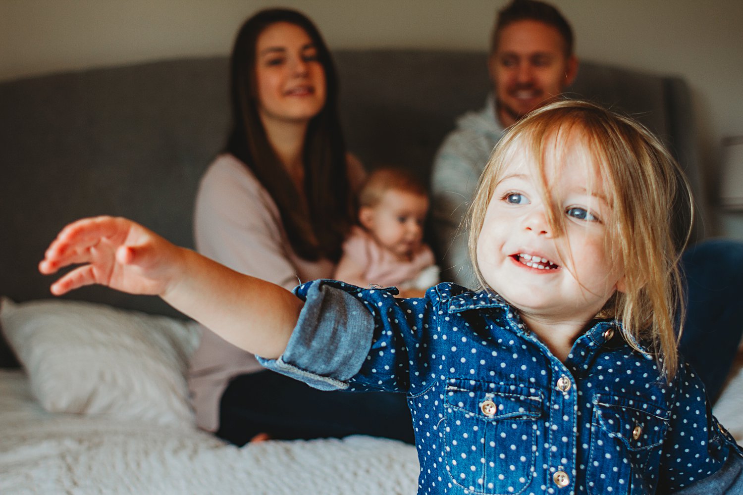 Lifestyle portrait of family on bed with two young children