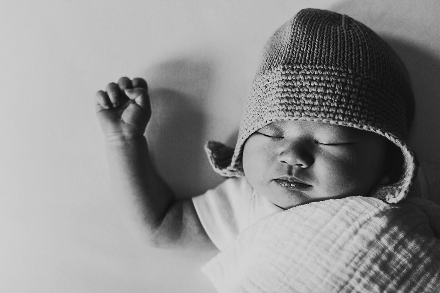 Sleeping newborn baby swaddled wearing hat