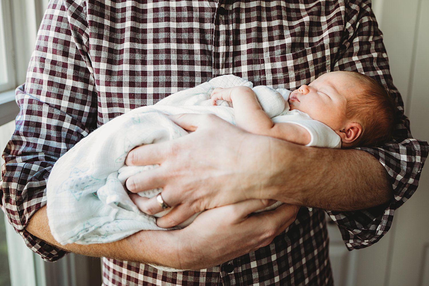 Lifestyle family portrait of dad holding newborn baby