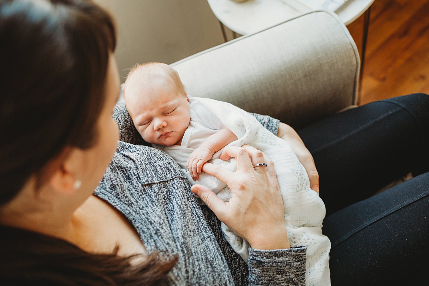 Mom holding onto newborn baby girl's finger